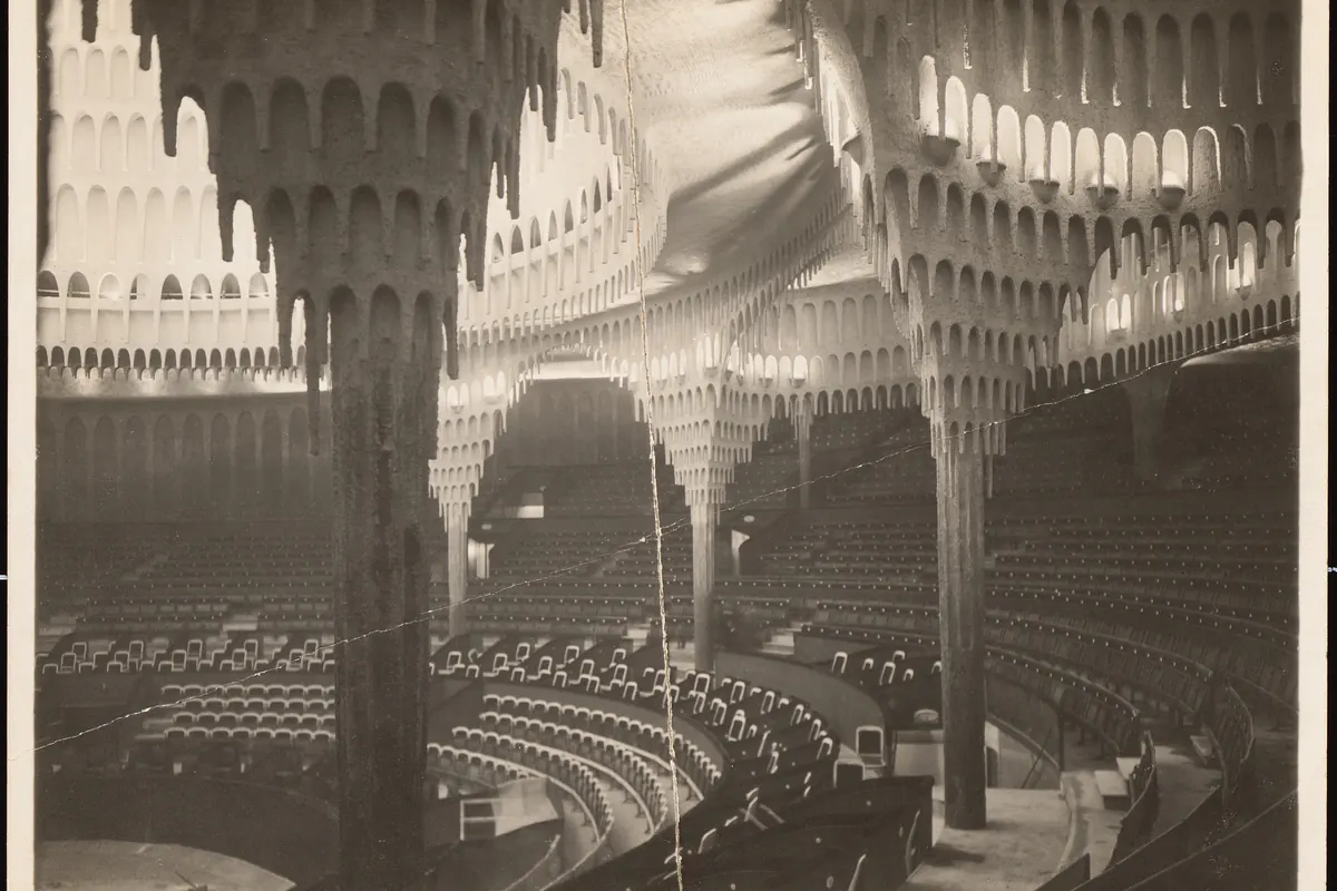 The ceiling and supporting columns of a domed auditorium covered in hanging plaster forms, photographed in black and white